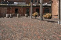 an industrially styled parking lot is dotted with brick bricks in a courtyard with many barrels on either side of the plaza