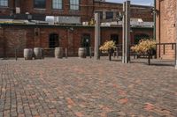 an industrially styled parking lot is dotted with brick bricks in a courtyard with many barrels on either side of the plaza