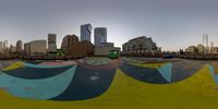 there is a large mural in the middle of the skate park with tall buildings in the background