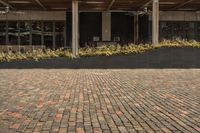 a person sitting in front of the food hall on a brick ground with an open umbrella over them