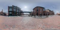 a very wide angle fish eye view of a big brick building and a road that runs through it