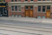 an open door to an old brick building with railroad tracks below it and steps going up the left side of the street