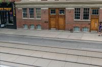 an open door to an old brick building with railroad tracks below it and steps going up the left side of the street