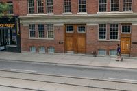 an open door to an old brick building with railroad tracks below it and steps going up the left side of the street