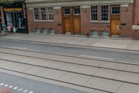 an open door to an old brick building with railroad tracks below it and steps going up the left side of the street