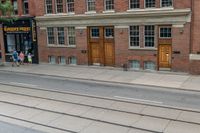 an open door to an old brick building with railroad tracks below it and steps going up the left side of the street