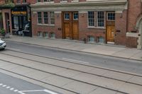 an open door to an old brick building with railroad tracks below it and steps going up the left side of the street