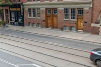 an open door to an old brick building with railroad tracks below it and steps going up the left side of the street