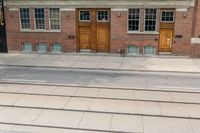 an open door to an old brick building with railroad tracks below it and steps going up the left side of the street