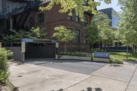 a sidewalk is near the building next to trees and a sidewalk lamp and stairs on the right side