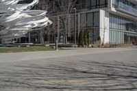 the sculpture has several white strips of fabric attached to it, by some trees and a walkway