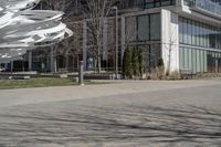 the sculpture has several white strips of fabric attached to it, by some trees and a walkway