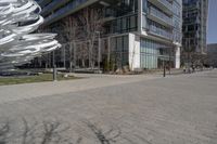 the sculpture has several white strips of fabric attached to it, by some trees and a walkway