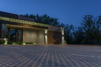 the front of a public building lit up at night with lights on, and sign saying presentation gallery