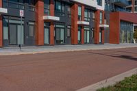 a sidewalk with a bicycle lane next to a building and street signs on the side of it