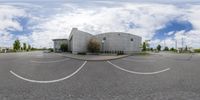 the view from a fish - eye lens of a large building near parking spaces on a street