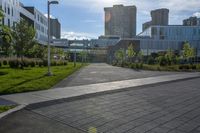 a city street surrounded by grass and tall buildings at the end of a street there is a paved pathway in front of the building