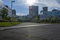 a city street surrounded by grass and tall buildings at the end of a street there is a paved pathway in front of the building