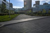 a city street surrounded by grass and tall buildings at the end of a street there is a paved pathway in front of the building