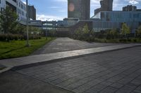 a city street surrounded by grass and tall buildings at the end of a street there is a paved pathway in front of the building