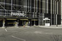 a parking garage with an entrance to it and some vehicles parked in the area behind it