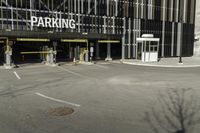 a parking garage with an entrance to it and some vehicles parked in the area behind it