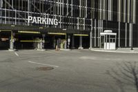 a parking garage with an entrance to it and some vehicles parked in the area behind it