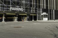 a parking garage with an entrance to it and some vehicles parked in the area behind it