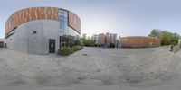 360 - lens image of two people walking past the library building and some buildings in background