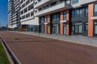 the empty road runs between a row of buildings near a grassy area near a brick sidewalk