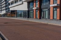 the empty road runs between a row of buildings near a grassy area near a brick sidewalk