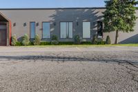 a gray building sitting on the street in front of a parkoure park and a parking area