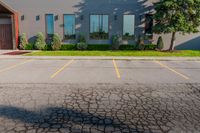 a gray building sitting on the street in front of a parkoure park and a parking area