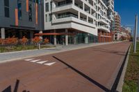 an empty street next to a residential building with balconies and a sidewalk on each side