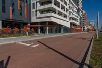 an empty street next to a residential building with balconies and a sidewalk on each side