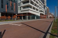 an empty street next to a residential building with balconies and a sidewalk on each side