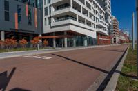 an empty street next to a residential building with balconies and a sidewalk on each side