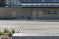 a concrete and glass building has a bench in front of it in the city street