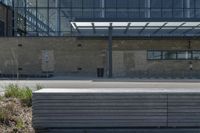 a concrete and glass building has a bench in front of it in the city street