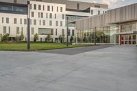 a city street surrounded by grass and tall buildings at the end of a street there is a paved pathway in front of the building