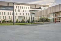 a city street surrounded by grass and tall buildings at the end of a street there is a paved pathway in front of the building