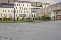 a city street surrounded by grass and tall buildings at the end of a street there is a paved pathway in front of the building