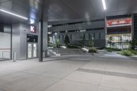 a large concrete building with windows and steps inside it at night, along with a car parking lot