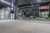 a large concrete building with windows and steps inside it at night, along with a car parking lot