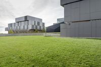 a grassy green yard next to two building with multiple structures of metal panels on the side