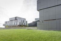 a grassy green yard next to two building with multiple structures of metal panels on the side