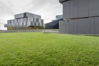 a grassy green yard next to two building with multiple structures of metal panels on the side