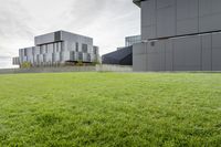 a grassy green yard next to two building with multiple structures of metal panels on the side