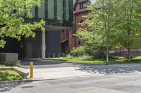 a street corner with a building, trees and bench in the foreground and a tree in front of it