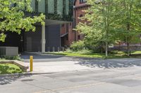 a street corner with a building, trees and bench in the foreground and a tree in front of it